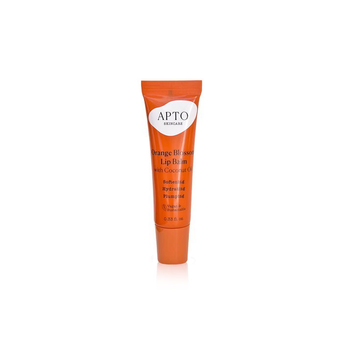 An orange tube of APTO Skincare Orange Blossom Lip Balm with Coconut Oil, featuring text that highlights its softening, hydrating, and plumping properties. The tube is upright on a white background.