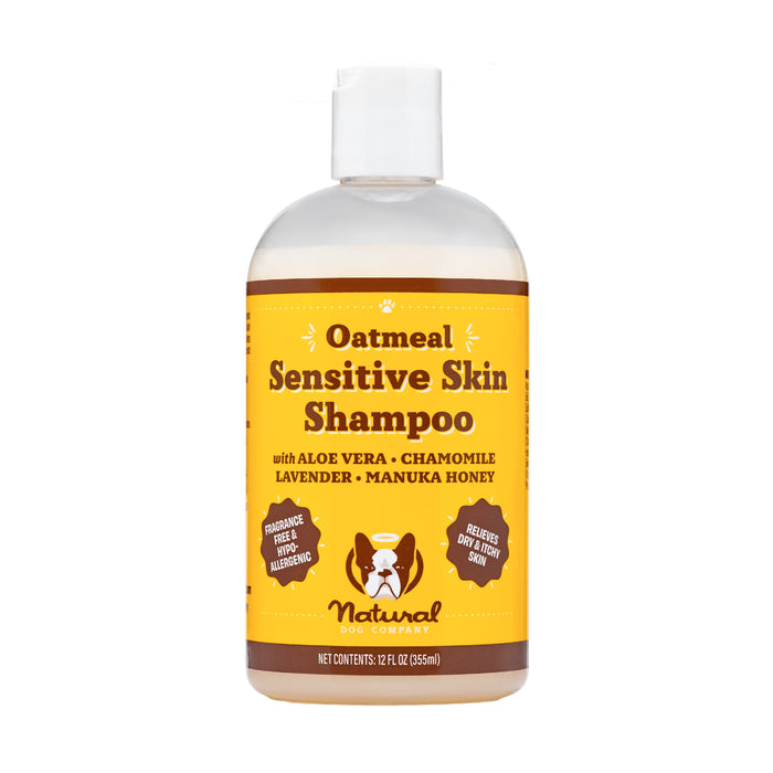 A clear bottle of Oatmeal Sensitive Skin Shampoo for dogs by Natural Dog Company, featuring ingredients like aloe vera, chamomile, lavender, and manuka honey. The label highlights benefits for dry, itchy skin.