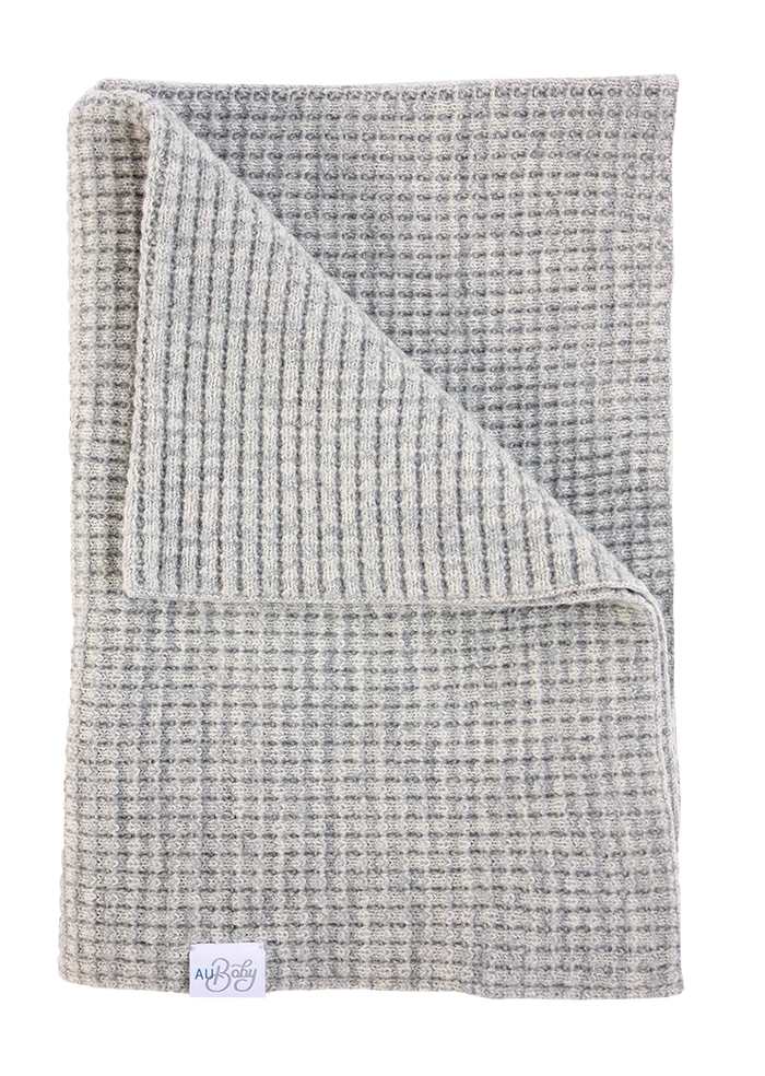 A folded light gray, waffle-knit AU Baby The Popcorn Blanket - Moon Stone, featuring a white label in the corner.