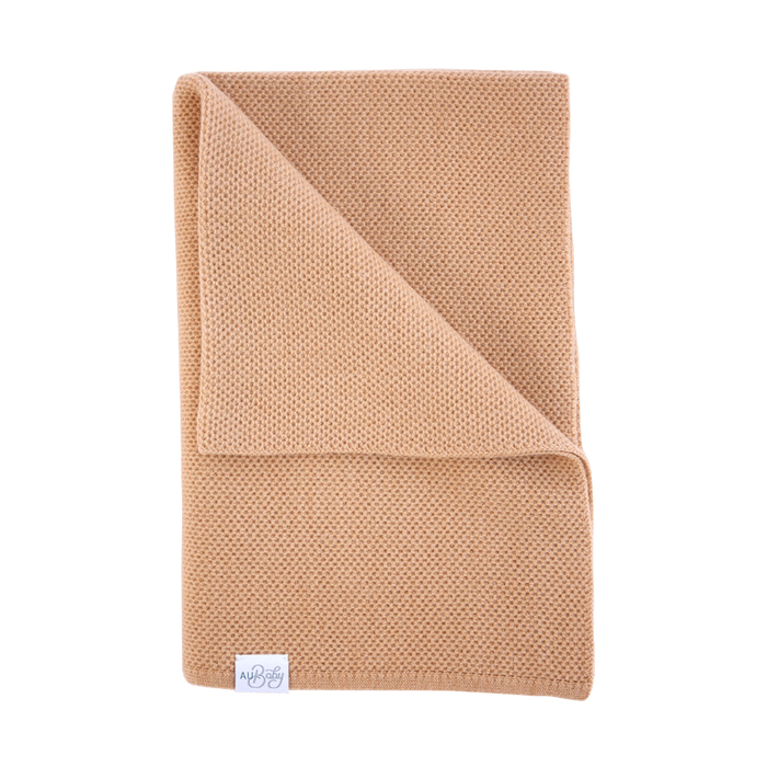 The Sawa - Henna baby blanket, folded in a textured, plant-dyed merino knit pattern.