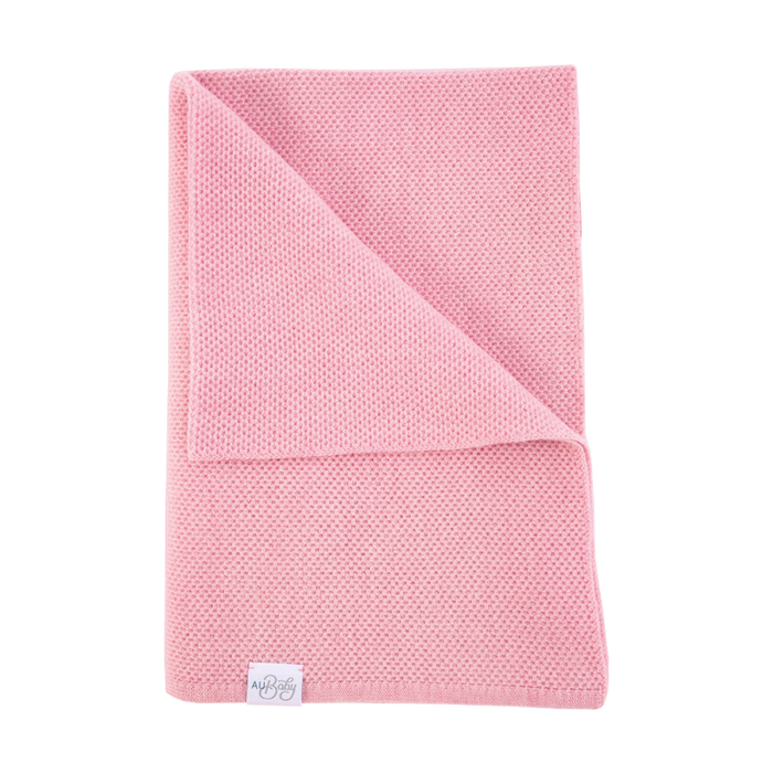 A folded The Sawa - Pink Quartz baby blanket by AU Baby in pink knit with a small white brand label at the bottom corner.