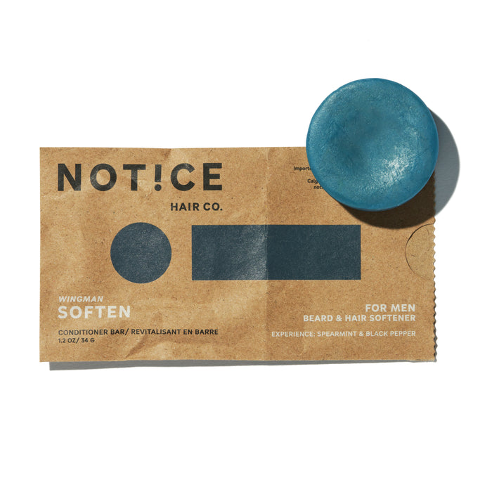 A round blue conditioner bar sits on top of brown packaging labeled NOTICE Hair Co. Wingman Soften Conditioner Bar for Men—Beard & Hair Softener, Spearmint & Black Pepper.