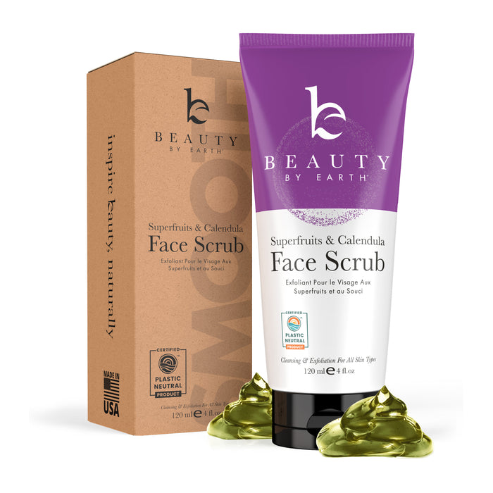 A tube of Beauty by Earth Superfruits & Calendula Face Scrub sits next to its box, with green scrub gel in front. The packaging is purple and beige, labeled vegan and plastic neutral.