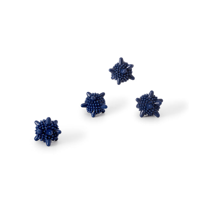 Four small, dark blue, spiky, spherical objects are arranged on a white background. Each object has multiple protruding points and a textured surface.