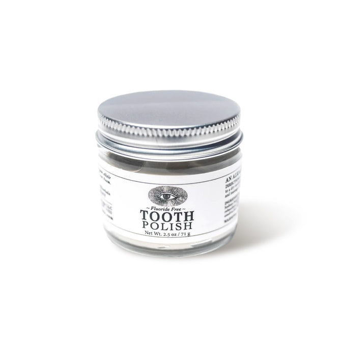 A small clear glass jar of Anima Mundi TOOTH POLISH, Fluoride Free, Net Wt. 2.5 oz / 71 g, with a silver lid on a white background, featuring a plant-based clay formula for naturally brighter smiles.