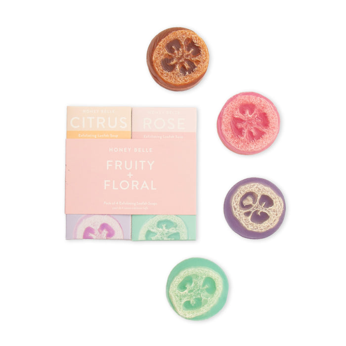Four round, colorful exfoliating loofah soaps—orange, pink, purple, and green—are arranged around a pastel-colored box labeled Honey Belle Fruity + Floral Exfoliating Loofah Soap.