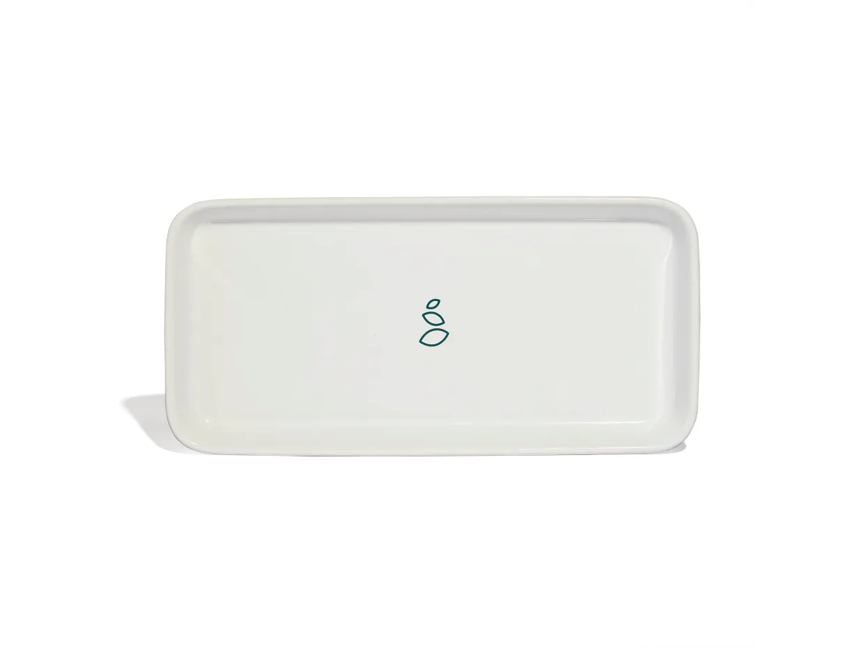 A rectangular white ceramic tray with rounded edges, featuring a small, simple green geometric design in the center. The background is plain and white.