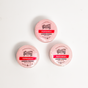 Three round, pink Spinster Sisters Co. Peppermint Shower Steamers are arranged in a triangle on a white background. Each is wrapped in plastic with a red and white label, ideal for an invigorating aromatherapy shower experience.