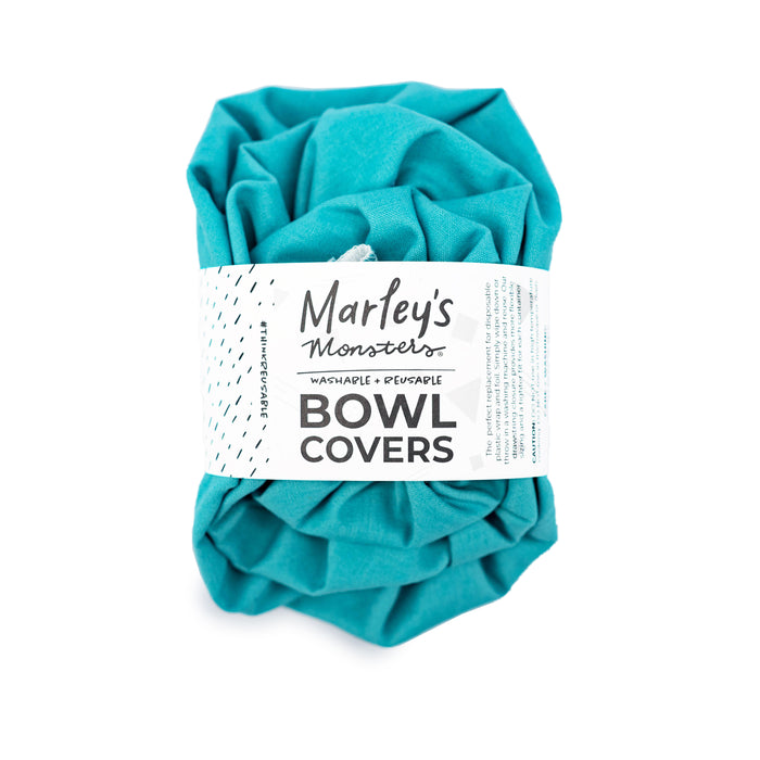 A teal reusable bowl cover by Marleys Monsters, folded and wrapped with a white product label that reads Marleys Monsters Washable + Reusable Bowl Covers.