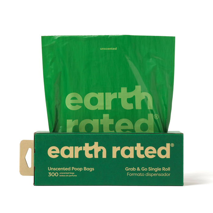 A green box labeled earth rated contains unscented poop bags. One large green bag is shown standing up behind the box. The box advertises a pack of 300 bags and features both English and Spanish text.