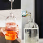 Split image: Left side shows a hand filling a reusable spray bottle with water from a tap; right side shows a bottle of Grove Co. solution being poured into a clear bottle filled with water.