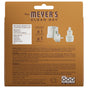 The back of a Mrs. Meyer's Premium Scented Oil Diffuser Kit refill shows the wall plug-in diffuser, scented oils, usage instructions, safety warnings, company info, and website links on a brown background.