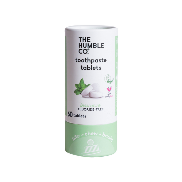 A cylindrical container of The Humble Co. toothpaste tablets in fresh mint flavor. The label indicates it is fluoride-free, vegan, cruelty-free, and contains 60 tablets. The packaging is mostly white and light green.