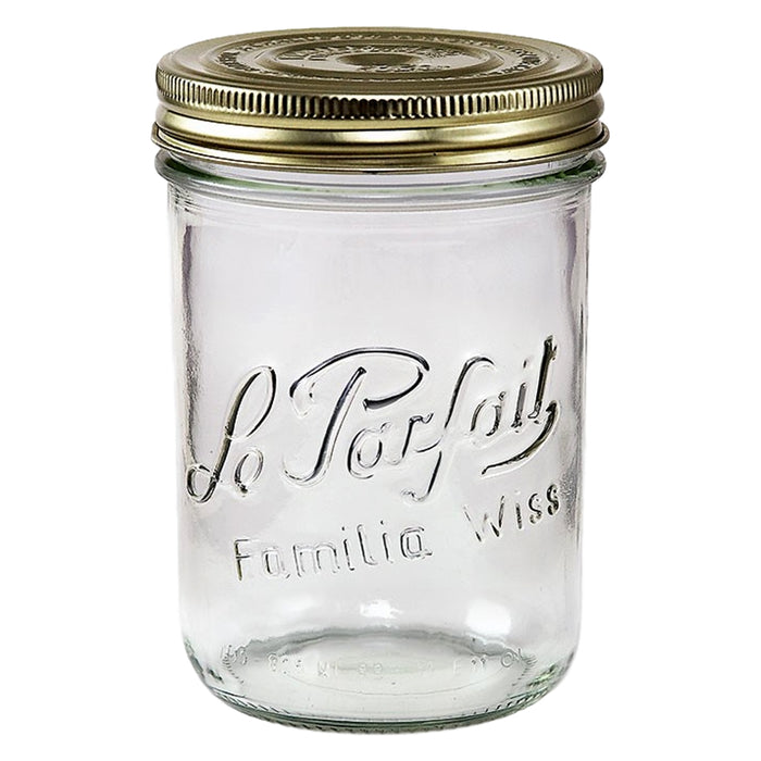 A clear glass jar with Le Parfait and Familia Wiss embossed on the front, topped with a double gold metal lid on a white background.