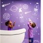 Two children in a pretend bathtub look up at space-themed doodles on a purple wall, including planets, stars, and illustrated bottles of shampoo and bubble bath. One child points while the other holds a bottle to their mouth.