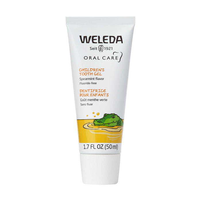 A white 1.7 fl oz (50 ml) tube of Weleda Childrens Tooth Gel, featuring green and orange text and a drawing of a green crocodile in water. The product is spearmint flavor and fluoride-free.