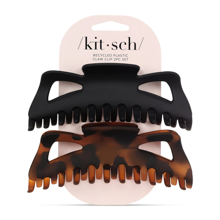 Two large claw hair clips, one matte black and one tortoiseshell, are attached to a white card labeled “kitsch Recycled Plastic Claw Clip 2pc Set.”.