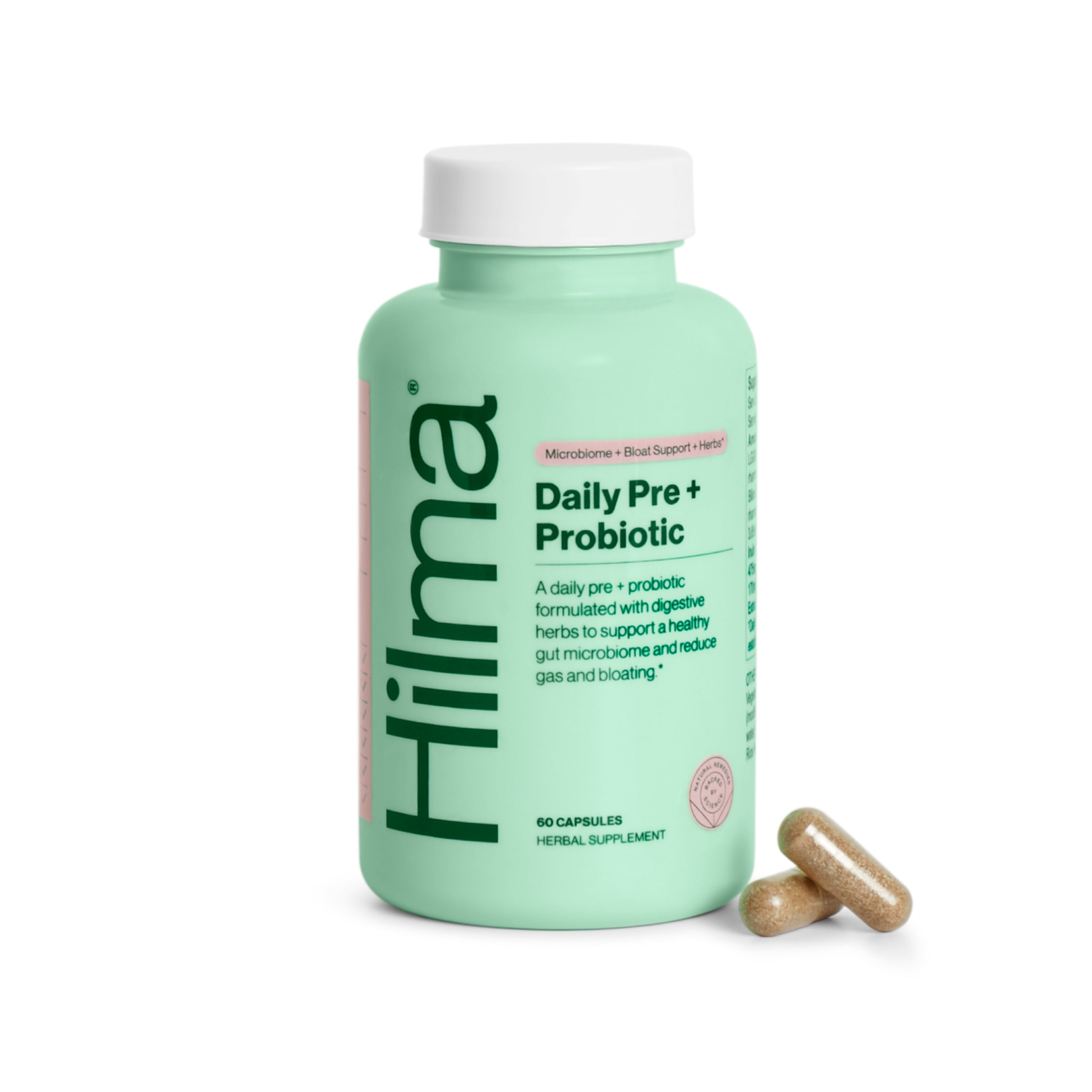 A green bottle labeled Hilma Daily Pre + Probiotic with 60 capsules, shown next to two beige capsules. The label highlights gut health support and contains digestible herbs.