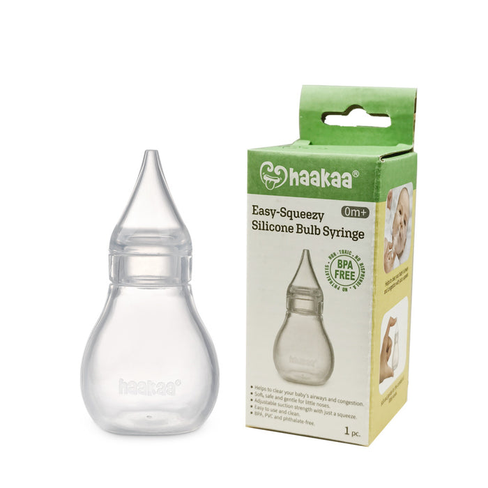 A clear silicone bulb syringe is shown next to its green and beige box packaging labeled haakaa Easy-Squeezy Silicone Bulb Syringe 0m+ BPA Free with an image of a baby on the box.