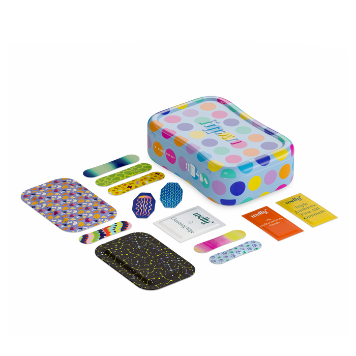 A colorful tin with polka dots is surrounded by assorted patterned bandages, two antiseptic wipe packets, and a small pack of gauze, all arranged neatly on a white background.