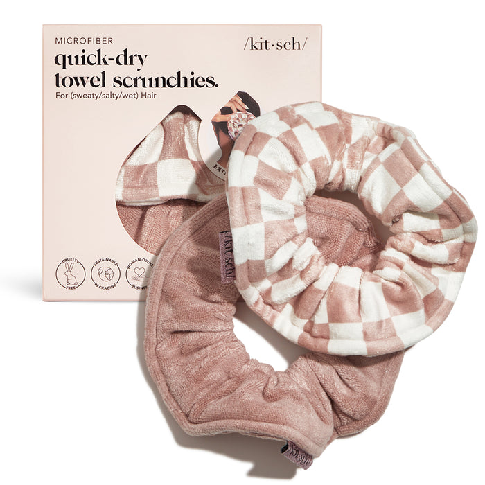 Two pink and white checkered and solid pink microfiber towel scrunchies are shown in front of their packaging, labeled kitsch quick-dry towel scrunchies for sweaty, salty, or wet hair.