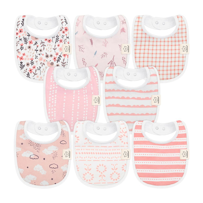 Seven baby bibs in shades of pink and white are arranged in two rows. Each bib features a different pattern, including florals, birds, gingham, clouds, stripes, dots, and abstract designs.