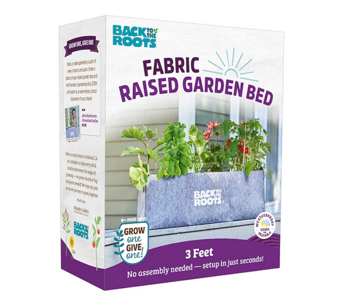 A box for Back to the Roots Fabric Raised Garden Bed shows a gray fabric planter with green plants. The packaging mentions its 3 feet long, easy to set up with no assembly, and includes the slogan Grow one, give one!.