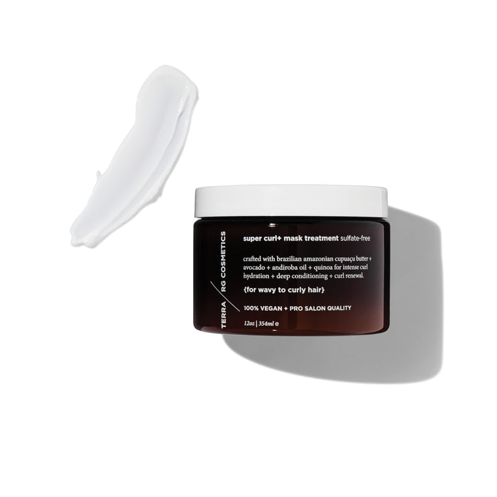 A brown jar labeled Super Curl+ Mask Treatment with white text sits on a white background. A smear of creamy white product is spread next to the jar. The lid is off, showing the product texture.
