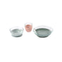 Three glass containers are shown: two contain clear liquid and one, in the center, contains a pink liquid. The containers are placed side by side on a white background.
