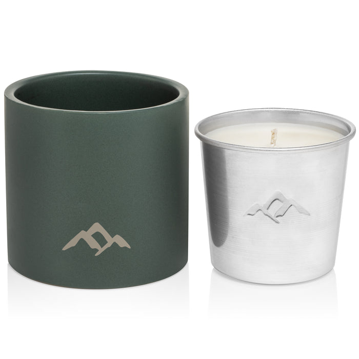 A green ceramic candle holder and a silver metal candle insert with white wax, both featuring a minimalist mountain logo on the front, displayed side by side on a white background.