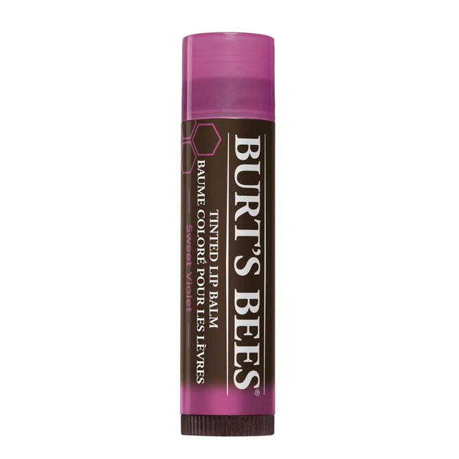 A tube of Burts Bees 100% Natural Tinted Lip Balm with a pink cap adds a pop of color, featuring a dark brown label with white text that beautifully showcases the brand name and product details.