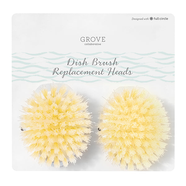 Two round, pale yellow dish brush replacement heads in plastic packaging labeled “Grove Collaborative Dish Brush Replacement Heads.”.