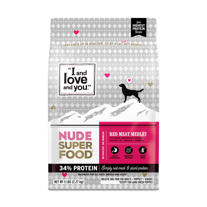 A bag of I and love and you Nude Super Food dry dog food, Red Meat Medley flavor, featuring a silhouette of a dog on mountains, pink and gray geometric hearts, and information about high protein and balanced nutrition.