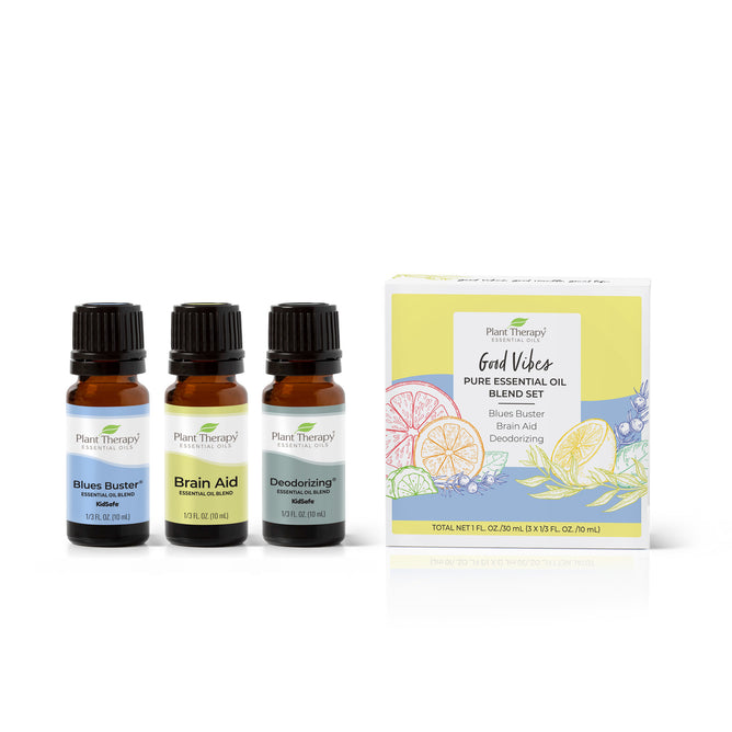 Three small amber bottles labeled “Blues Buster,” “Brain Aid,” and “Deodorizing” stand next to a box labeled “Good Vibes Pure Essential Oil Blend Set” with citrus fruit illustrations on the front.