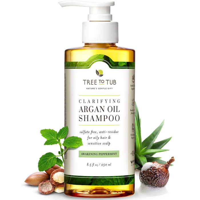 A bottle of Tree to Tub Clarifying Argan Oil Shampoo with a pump top, surrounded by argan nuts, peppermint leaves, shea nuts, and aloe vera, highlighting its natural ingredients.