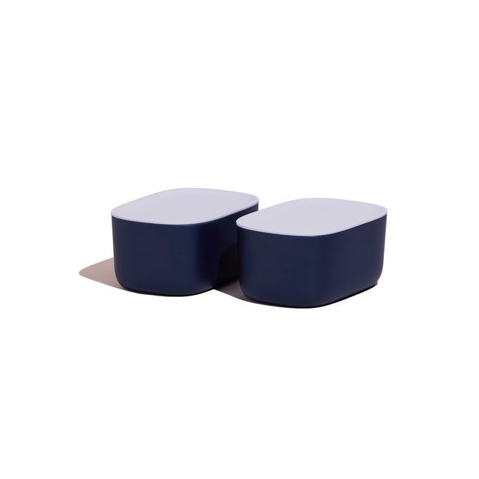 Two modern, rectangular containers with rounded edges, dark blue bases, and white lids, placed side by side on a white background.