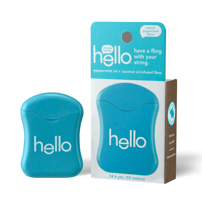 A blue container of hello brand dental floss stands next to its matching packaging, which is white and brown with turquoise accents. The packaging reads hello have a fling with your string.