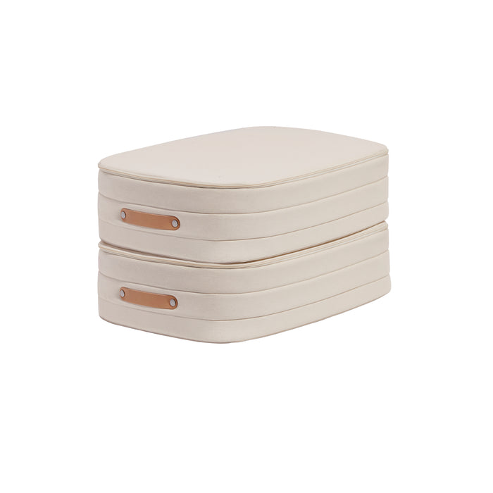 Two stacked, rectangular, beige fabric storage boxes with brown leather handles are shown against a white background.