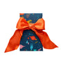 A Bees Wrap Reusable Gift Wrap in dark blue, featuring colorful animal and nature patterns, is topped with a shiny orange ribbon tied in a bow.