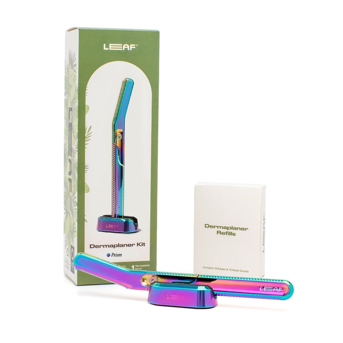 A colorful metallic dermaplaner tool is displayed with its stand, a box labeled “Dermaplaner Refills,” and green packaging marked “LEAF Dermaplaner Kit.” The tool has an iridescent finish.