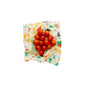 A cluster of small red tomatoes rests on Bees Wrap Assorted 3 Pack Holiday wraps—colorful, patterned, and plastic-free—for a festive, eco-friendly food display against a plain white background.