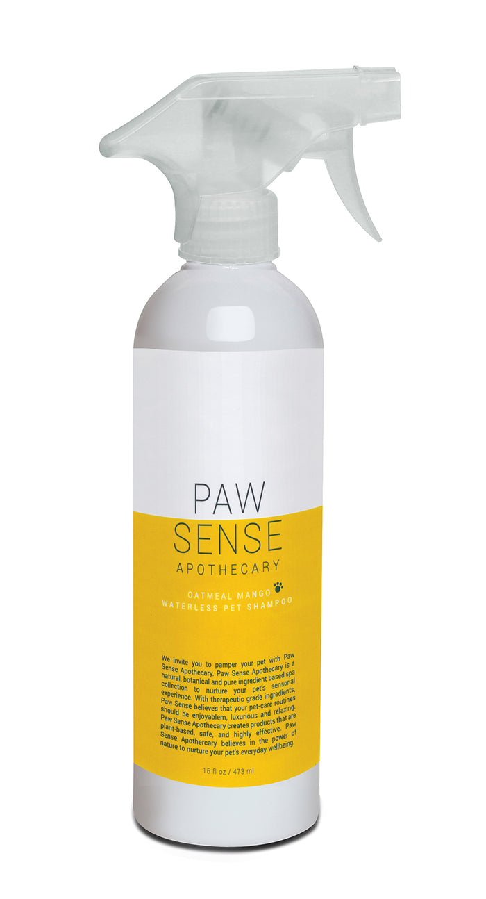A white spray bottle labeled Paw Sense Apothecary Oatmeal Mango Waterless Pet Shampoo with a yellow label and a transparent trigger nozzle.