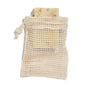 A speckled rectangular soap nestles in a beige, open-mesh Peach Soap Saver Bag, crafted from GOTS-certified cotton. Perfect for rich lather and exfoliation, the soap peeks out of the bag, set against a simple white background.