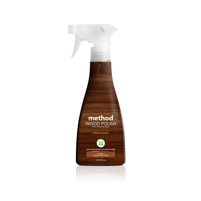 A clear spray bottle of Method Wood Polish in almond scent, featuring a brown wood grain label and white spray nozzle, standing upright on a white background.