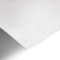 Close-up of a PurePower Enzymatic Laundry Detergent Sheet by Grove Co., featuring scattered multicolored specks. Reminiscent of active enzymes, the sheet slightly curls at the edge, casting a gentle shadow on the bright white surface beneath.