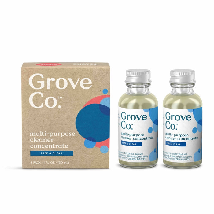 A box labeled Grove Co. multi-purpose cleaner concentrate sits next to two small glass bottles of the same cleaner, each with a blue cap and label. The packaging is beige with blue and red circular designs.