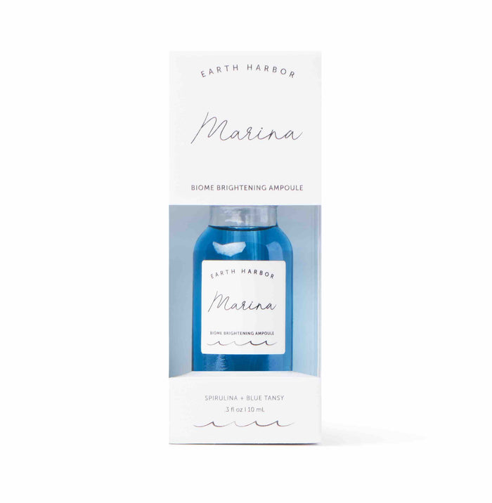 A blue glass bottle labeled Earth Harbor Marina is packaged in a white box with transparent front. The box reads Biome Brightening Ampoule and lists Spirulina + Blue Tansy, 1 oz / 30 mL at the bottom.