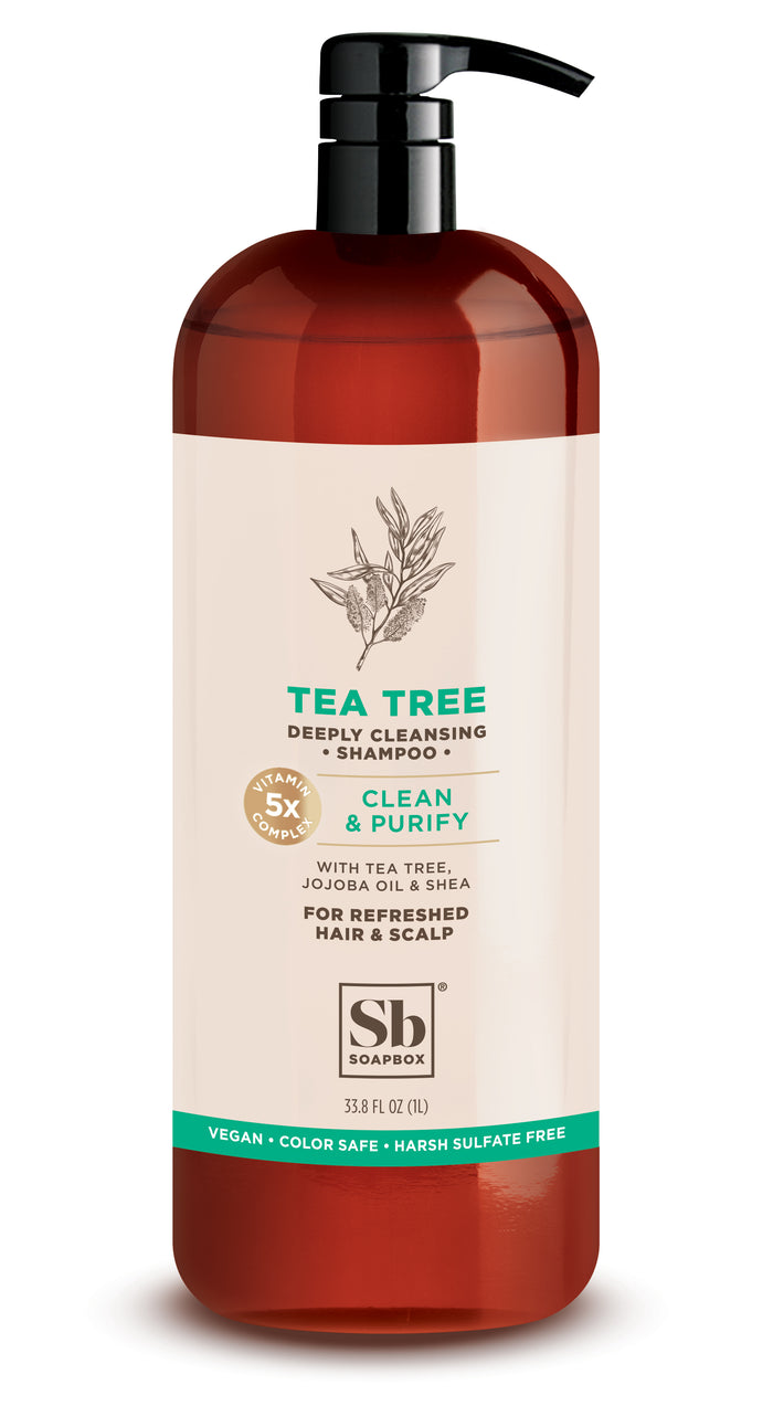 A brown pump bottle of Soapbox Tea Tree Deeply Cleansing Shampoo, featuring a minimalist label with plant illustration. Text highlights tea tree, jojoba oil, shea, and claims of being vegan, color safe, and sulfate-free.
