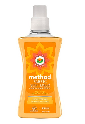 A bottle of Method fabric softener in a clear container with orange liquid, featuring an orange label that reads “Method Fabric Softener, ginger mango, scents + softens, reduces static cling.”.