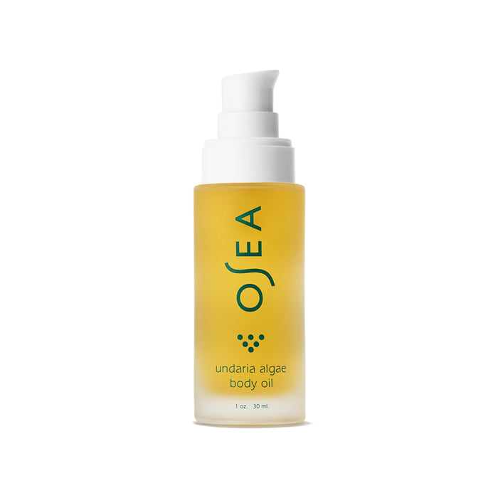 A clear frosted bottle with a white pump dispenser containing yellow OSEA undaria algae body oil, 1 oz size, with teal text and logo on the front, displayed against a white background.
